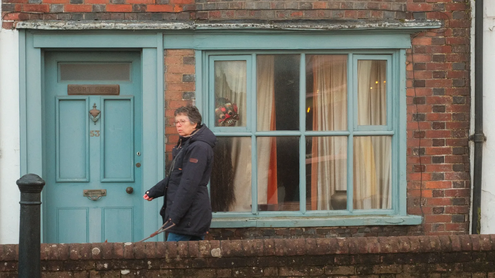 Woman walking past turquoise-painted shopfront in Emsworth