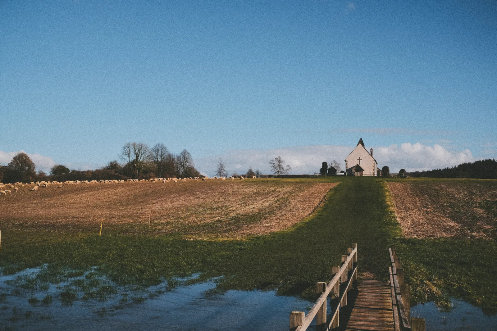 Small bridge to cross the flooded field, looking towards the church at the top of the hill
