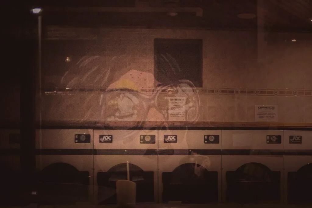 Laundromat interior at night with fluorescent lighting and empty chairs
